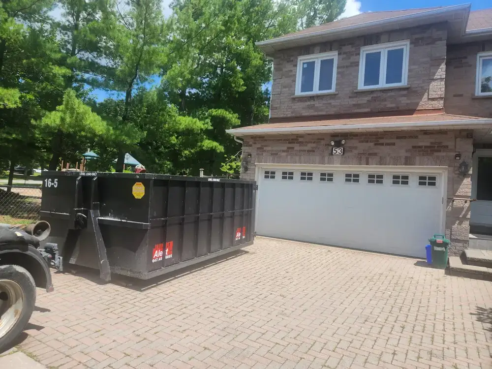 Roll-off bin on an interlock driveway in front of a double garage