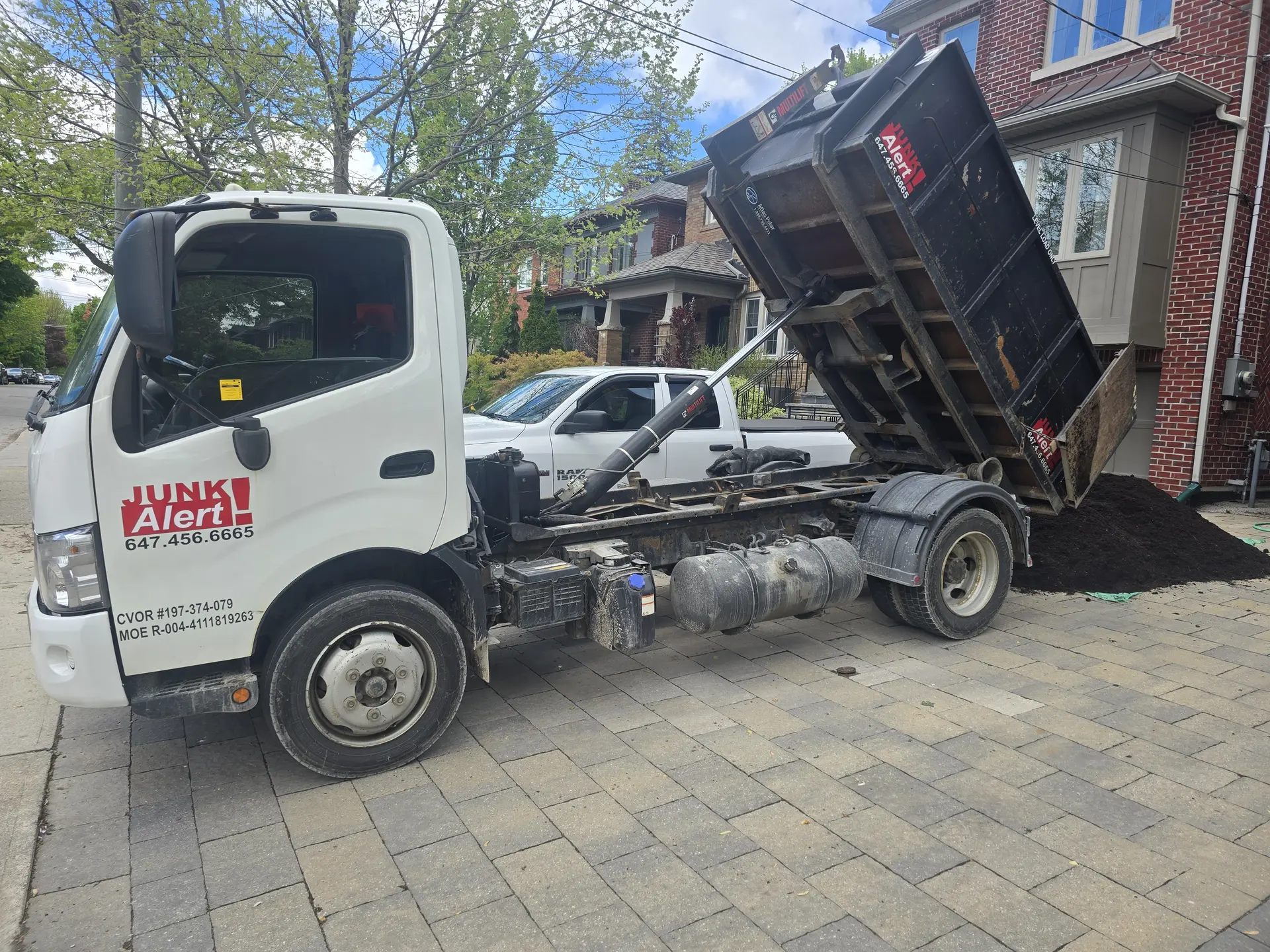 Junk Alert truck tipping a load of soil onto a driveway